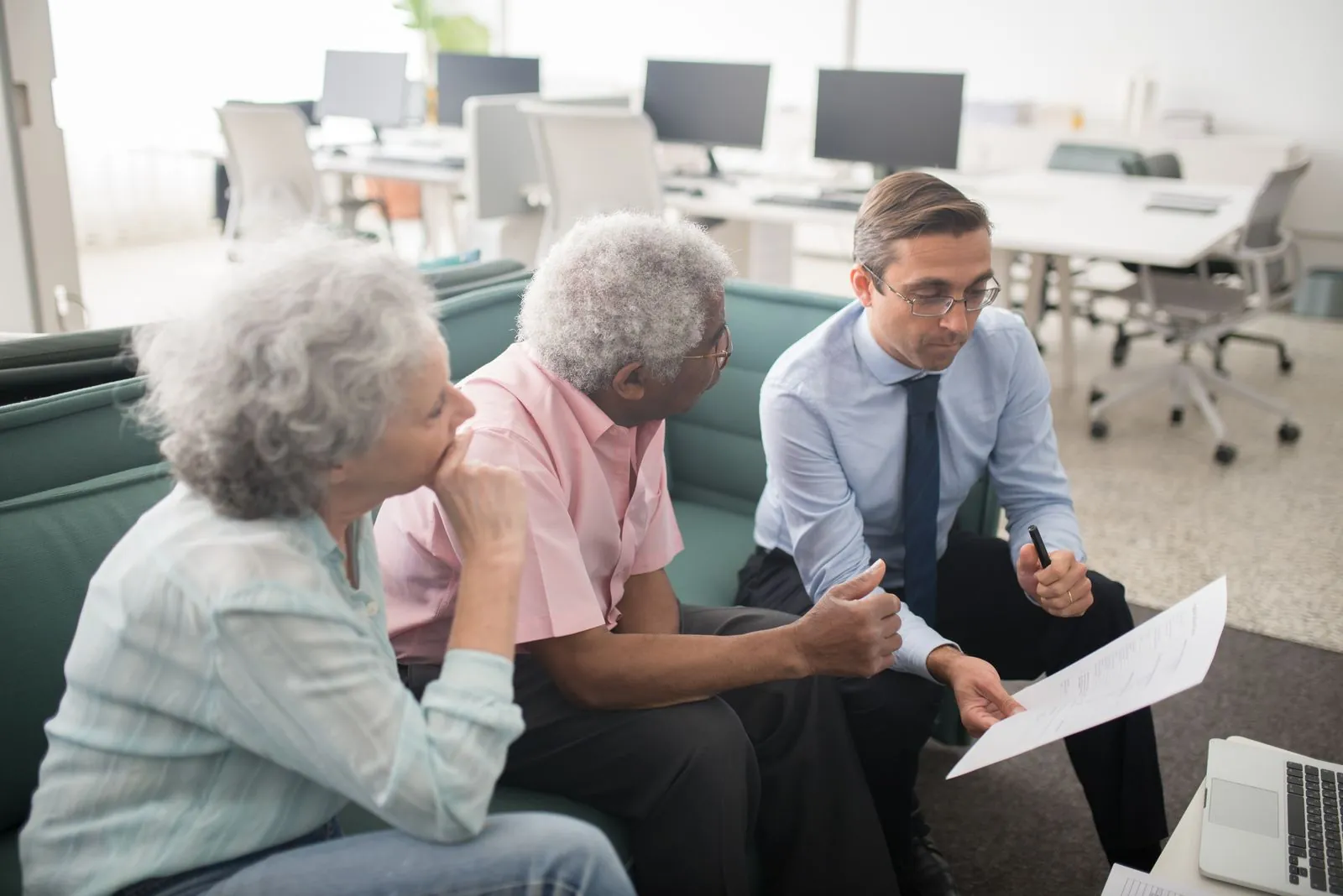Financial advisor reviewing a client's account on a laptop in a bright office